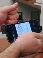user holding AllSee prototype attached to smartphone and gesturing with closed hand